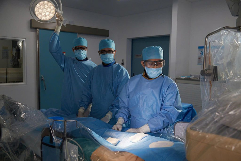 Ho Minh Tuan, MD, PhD (right) and his team place stents to restore the patient’s coronary artery.