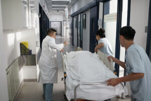 FV Hospital clinicians transferring a patient on a trolley along a hospital corridor